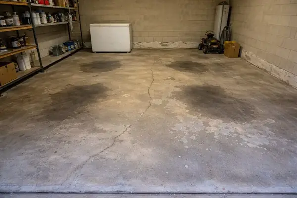 Worn, stained garage slab near the door before coating